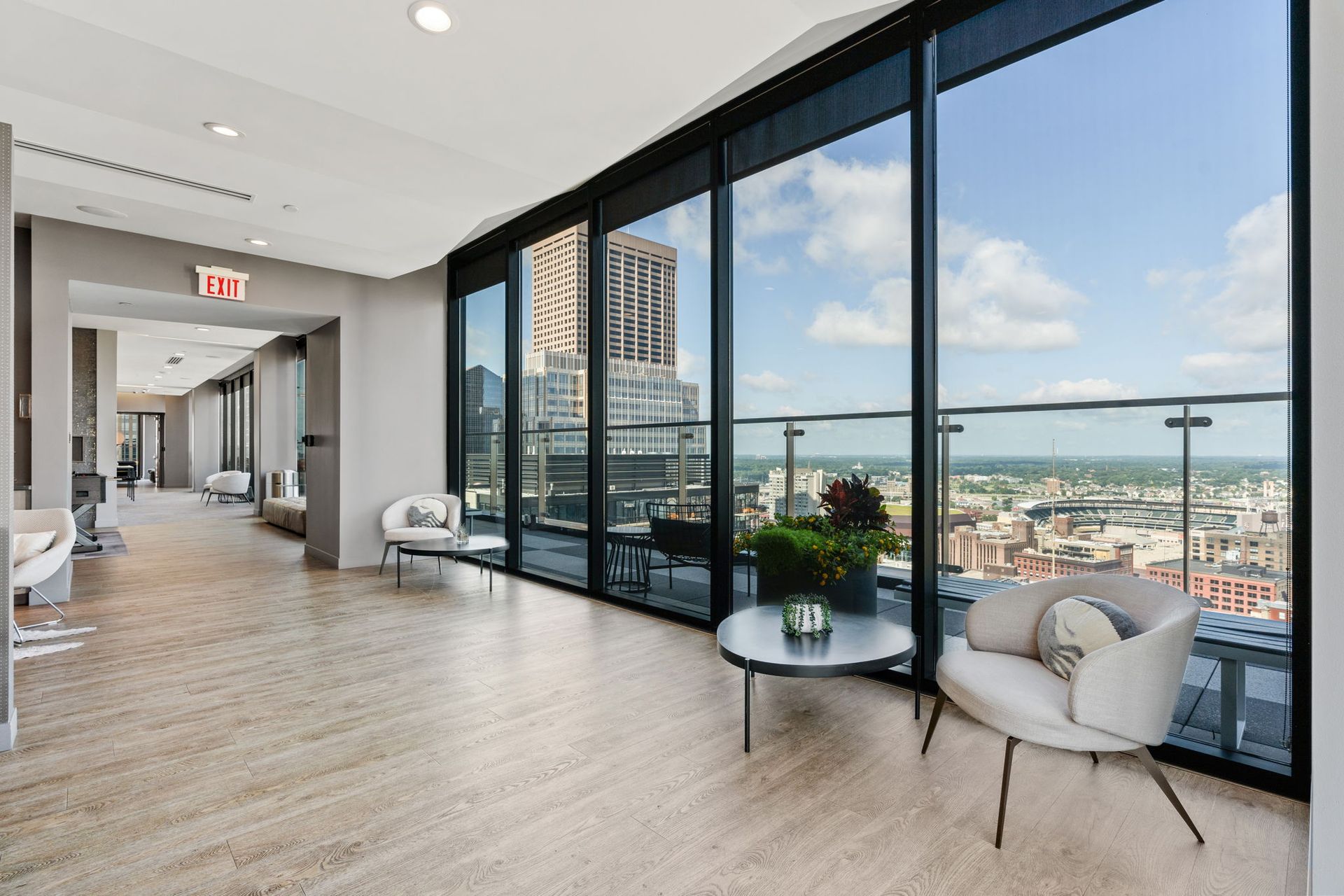Lounge with floor-to-ceiling windows overlooking a city. Two armchairs sit near a table.