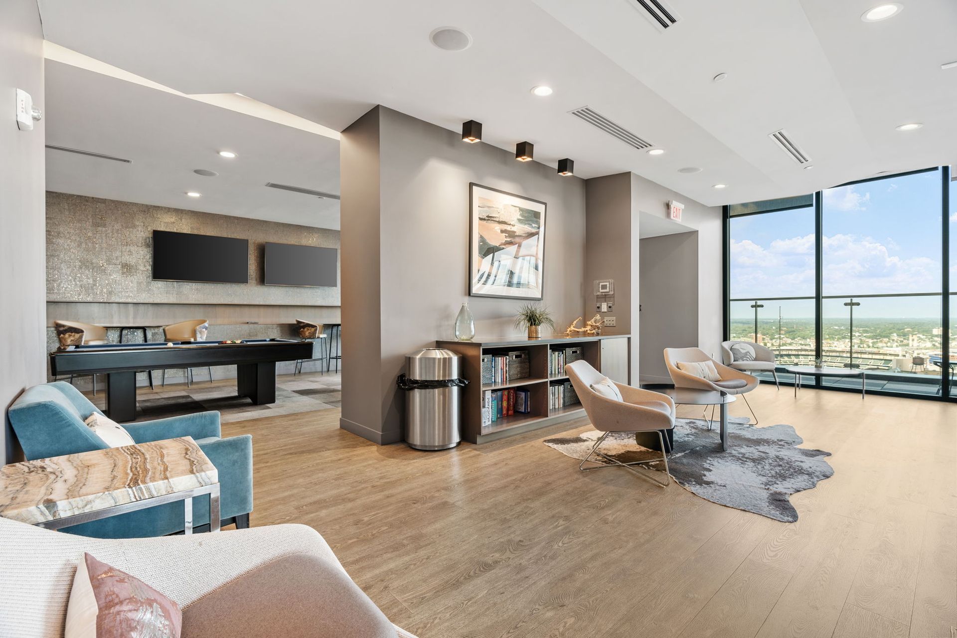 Modern lounge with seating, pool table, city view.