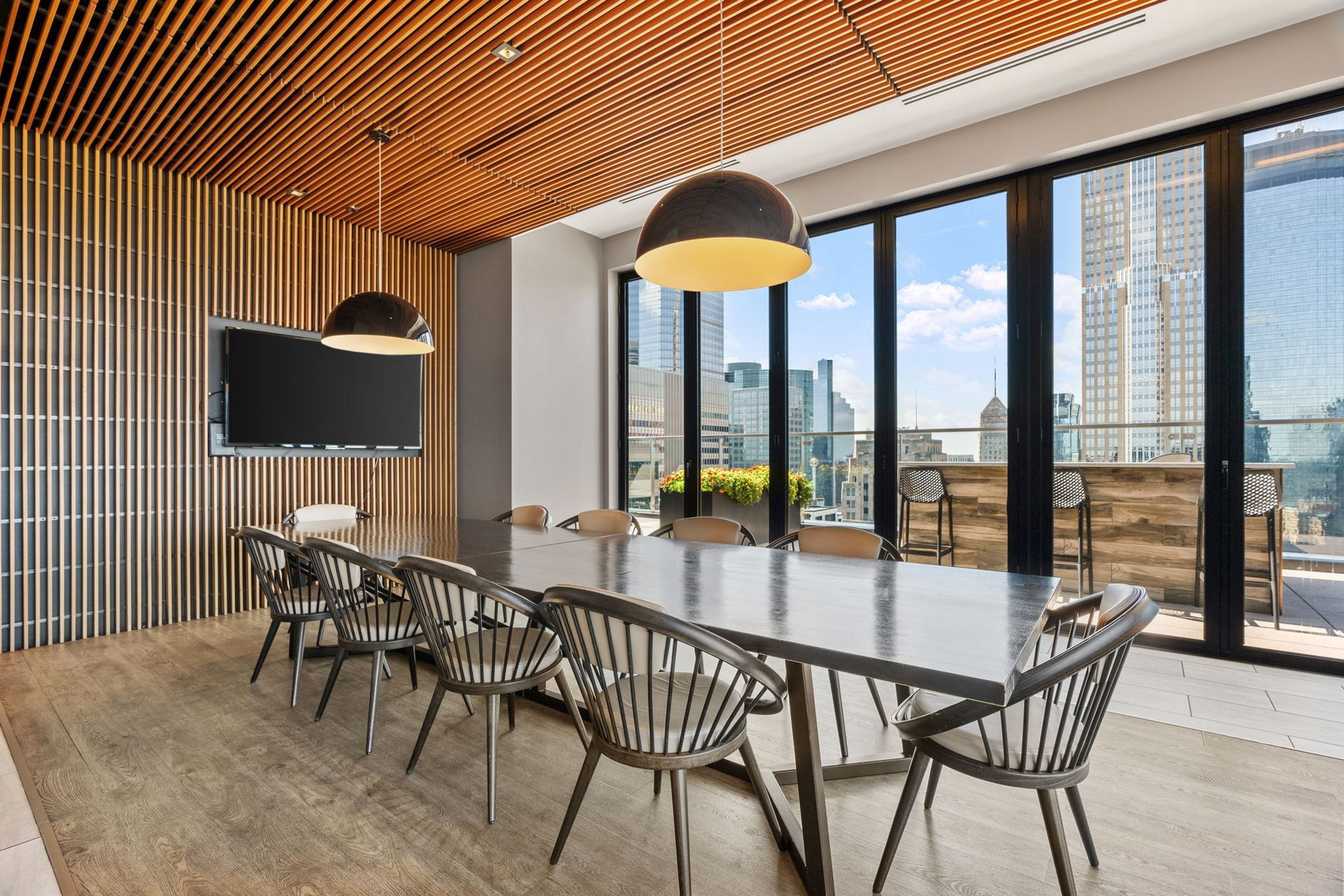 Conference room with a long table, chairs, city view through windows, and wooden paneling.