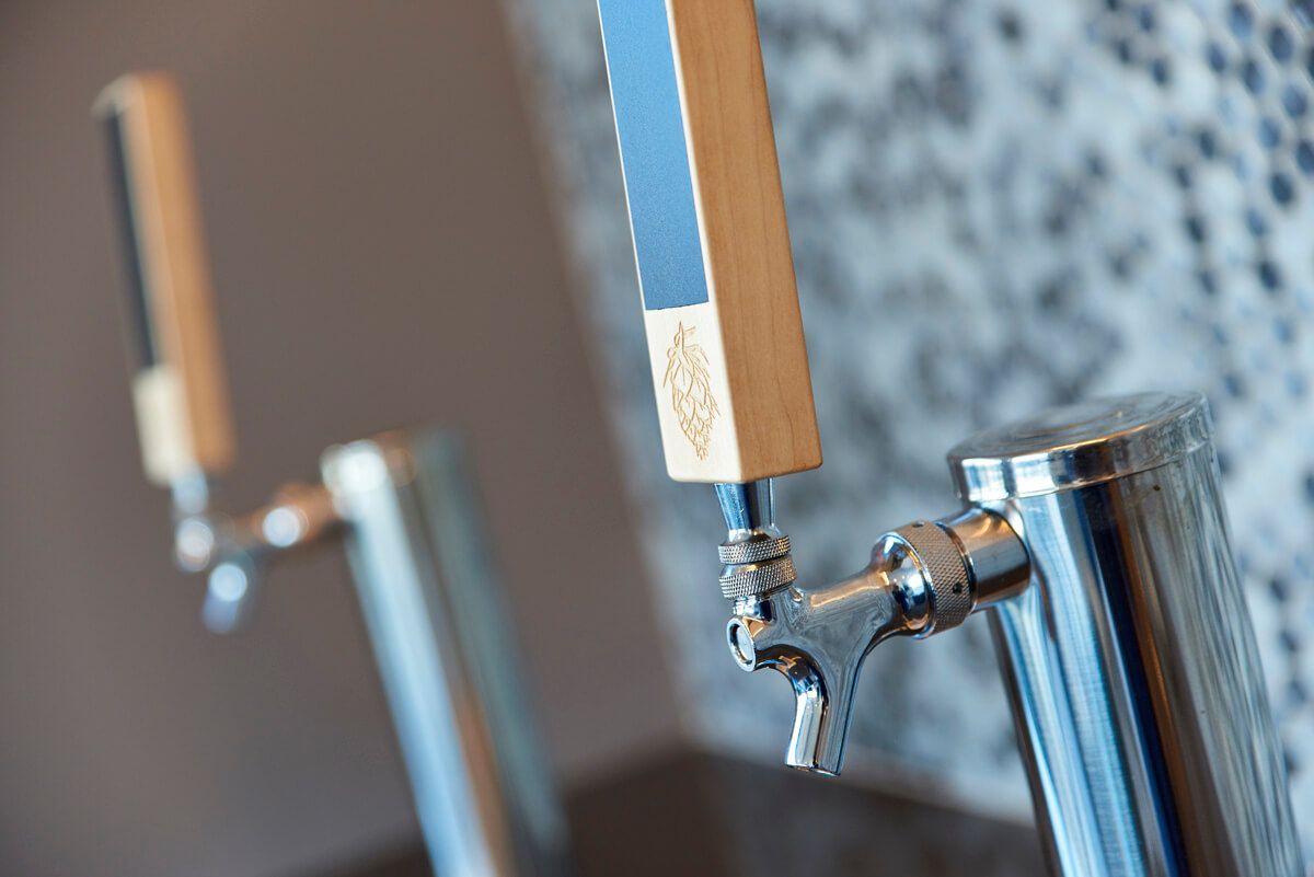 A close up of a beer tap with a wooden handle.