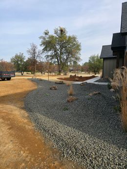 A gravel driveway leading to a house with a truck parked in the background.
