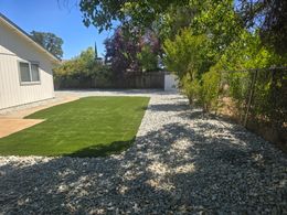 A sprinkler is spraying water on a lush green lawn in front of a house.