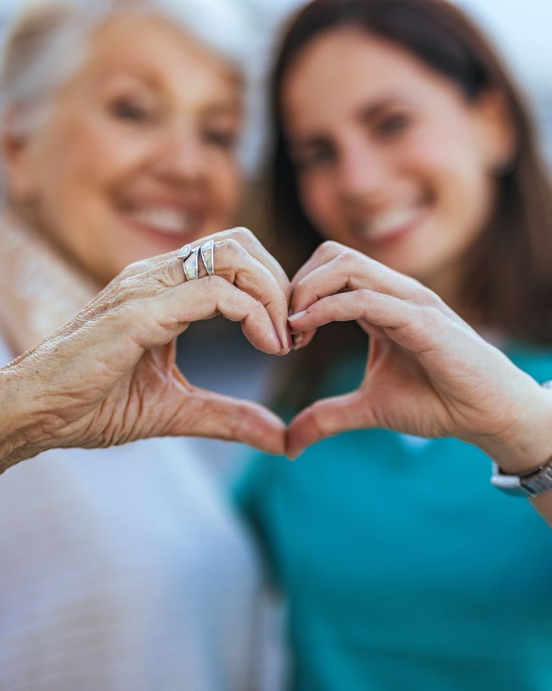 Two smiling people forming a heart shape with their hands.
