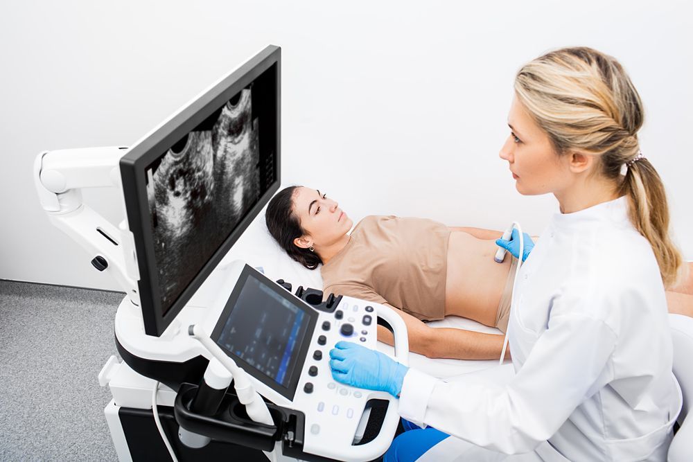 Woman receiving ultrasound scan from a medical professional in a clinical setting.