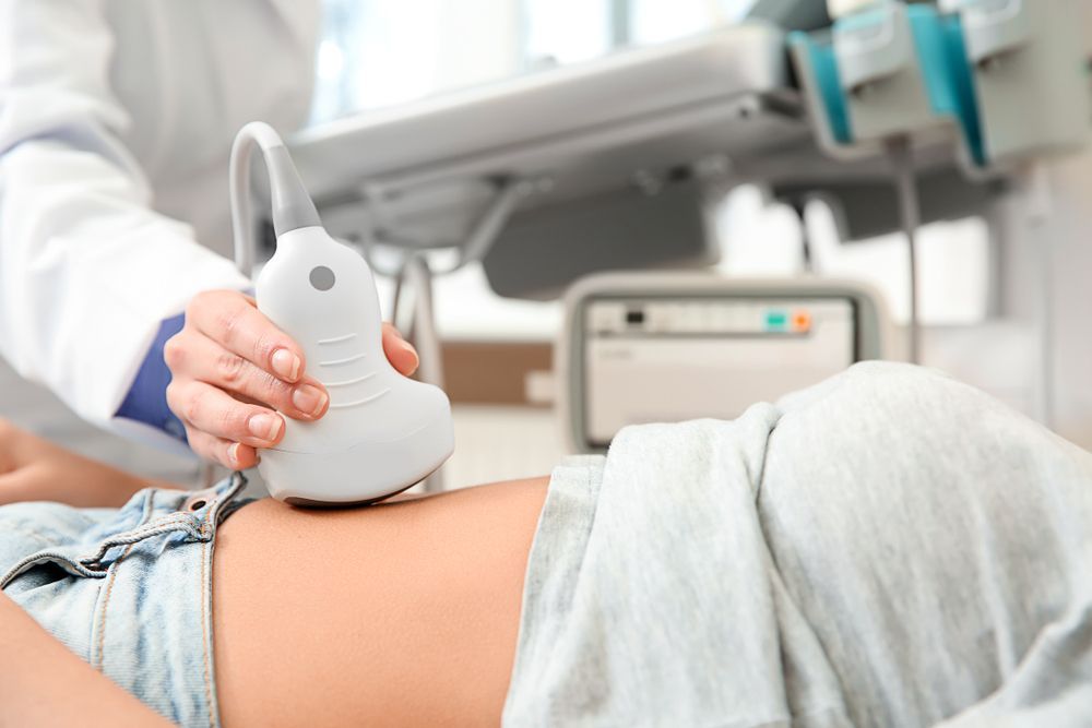 Person receiving an abdominal ultrasound exam. A technician holds the transducer on the abdomen.