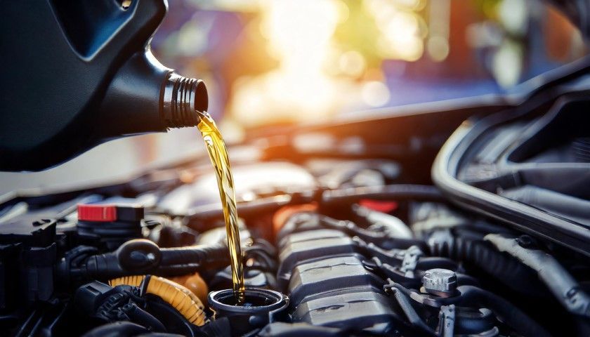 Motor oil pouring into a car engine bay during maintenance
