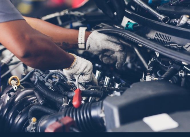 Mechanic’s gloved hands working on a car engine in a garage