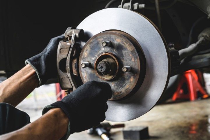 Mechanic using a tool to remove a car brake rotor in a garage
