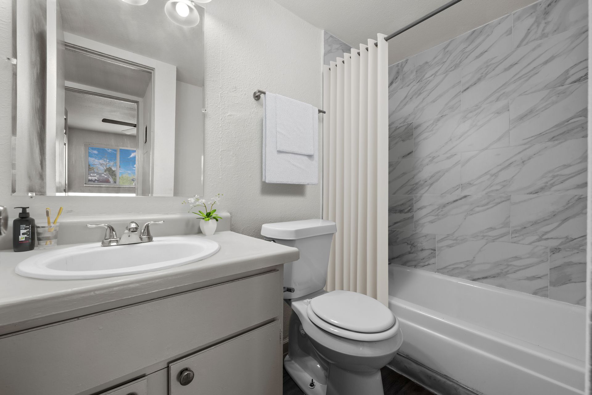 Photo showing a bathroom with a counter, vanity mirror, toilet and a bathtub/shower combo
