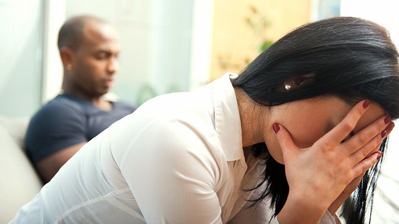 Woman crying with man sitting in background