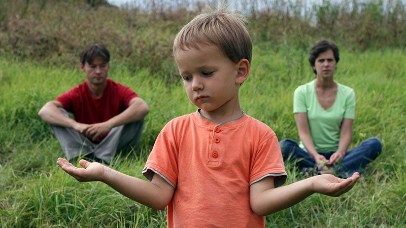 young child weighing options between mom and dad sitting in background