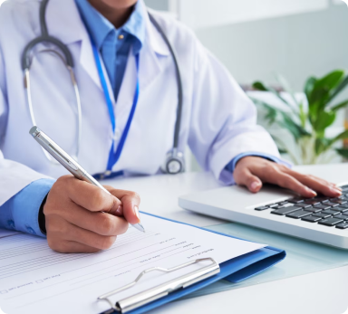 a doctor is writing on a clipboard while using a laptop