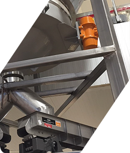 Maquinaria industrial metálica con estructura de acero y motor naranja en un entorno de fábrica.