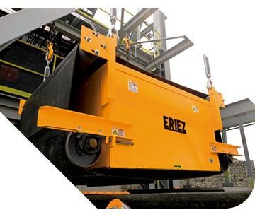 Maquinaria industrial ERIEZ de color naranja con componentes de cinta transportadora negros en un entorno de fábrica.