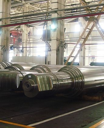 Grandes cilindros de metal pulido en una fábrica industrial con tuberías y vigas de acero suspendidas del techo.