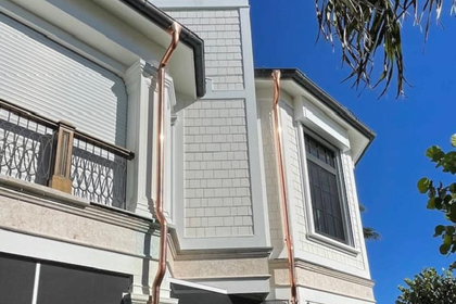 A white house with copper gutters on the side of it