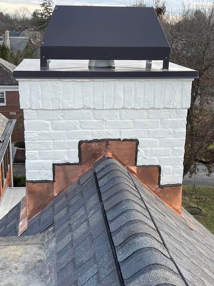 A chimney is sitting on top of a roof next to a house.