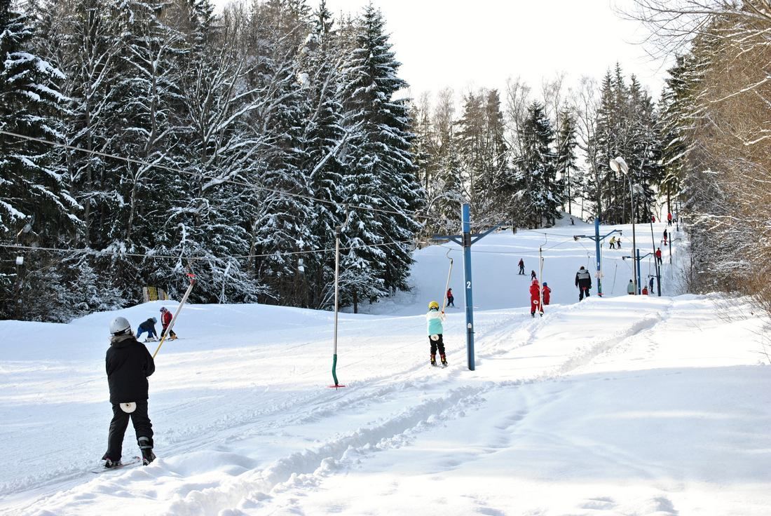 Wooden porch with rocking chairs. Doors lead to rooms. Sunny outdoor setting.
