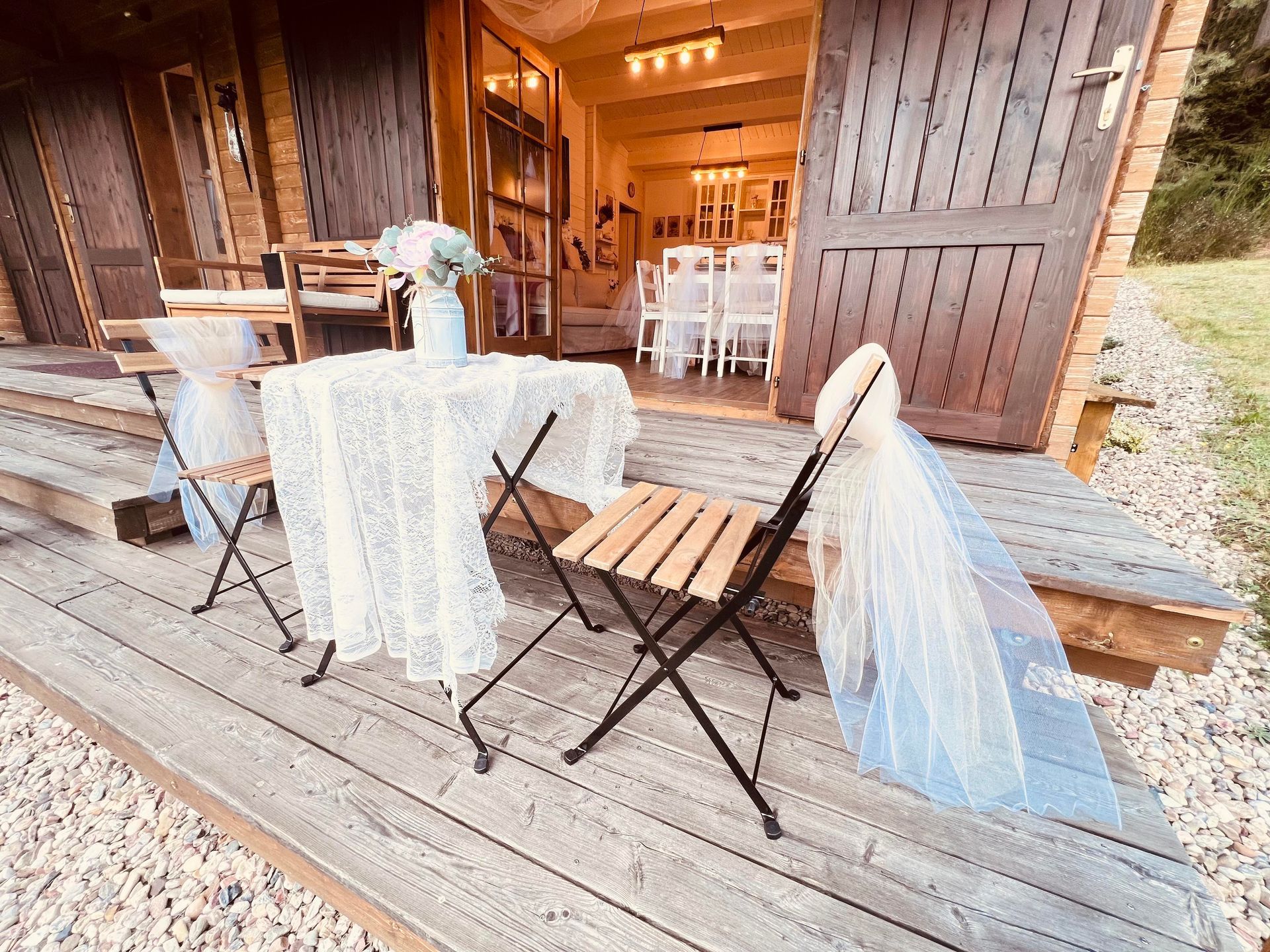 Outdoor seating area decorated for a wedding with white lace table and a sheer veil.