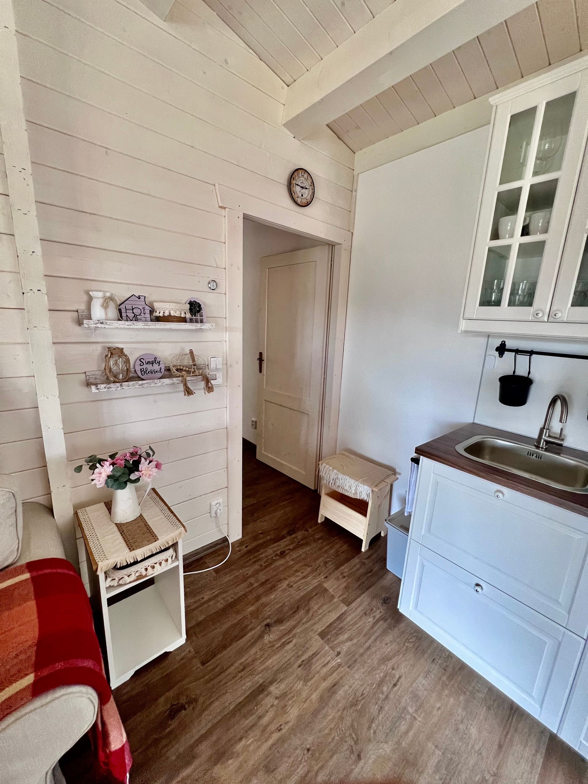 Small kitchen area with white cabinets, wood flooring, and an open doorway.