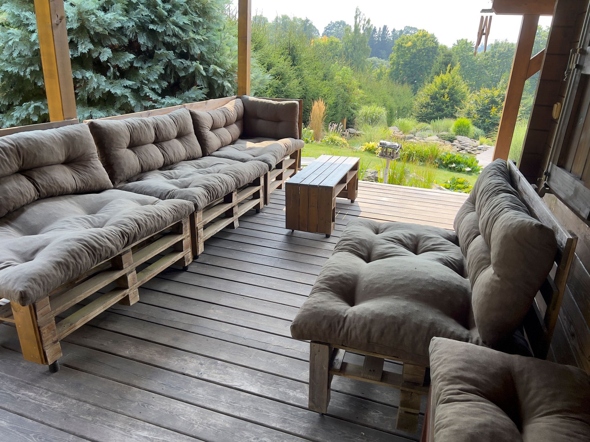 Outdoor seating area with pallet furniture and brown cushions.