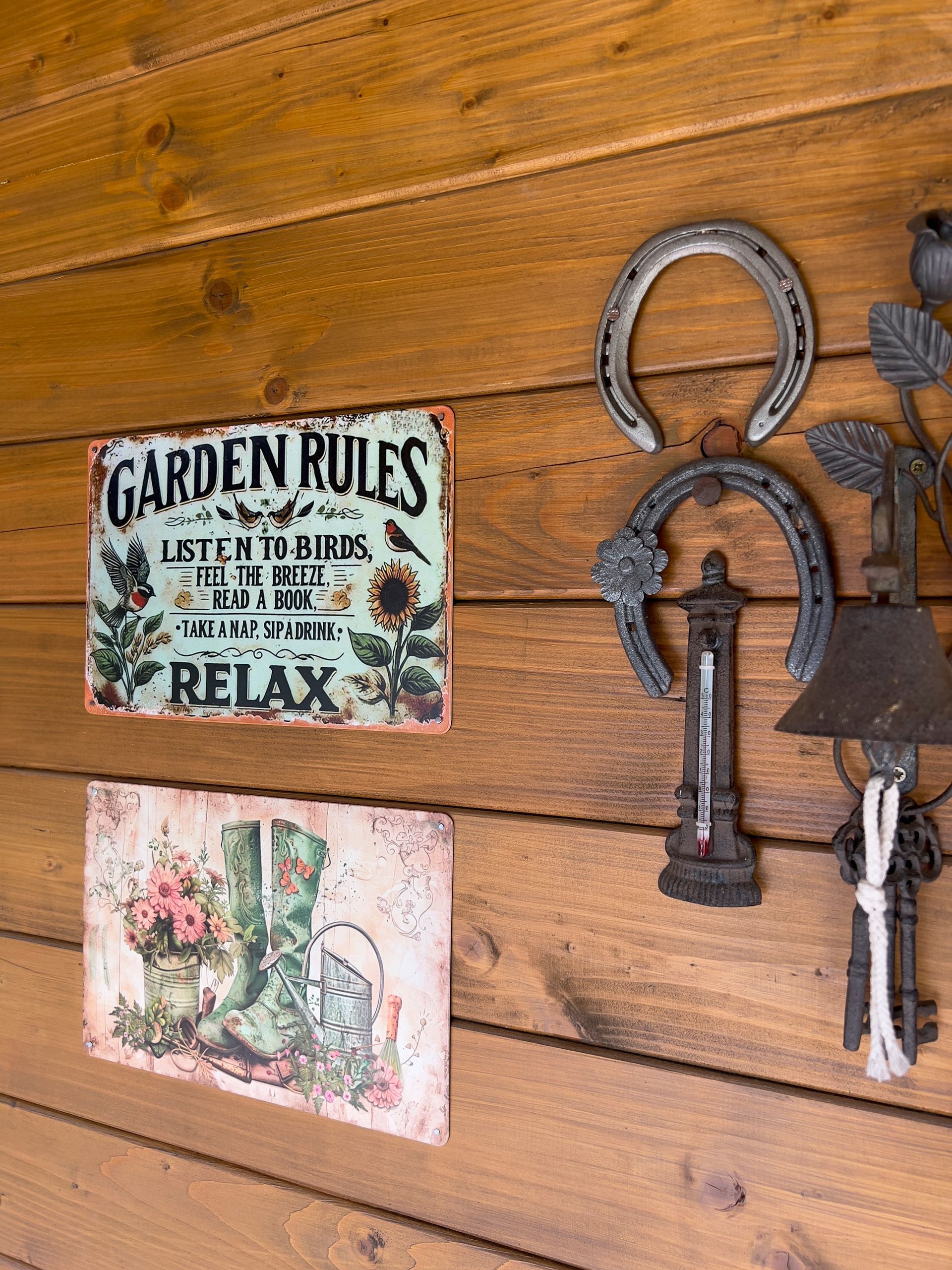Garden signs and metal decorations on a wood plank wall.