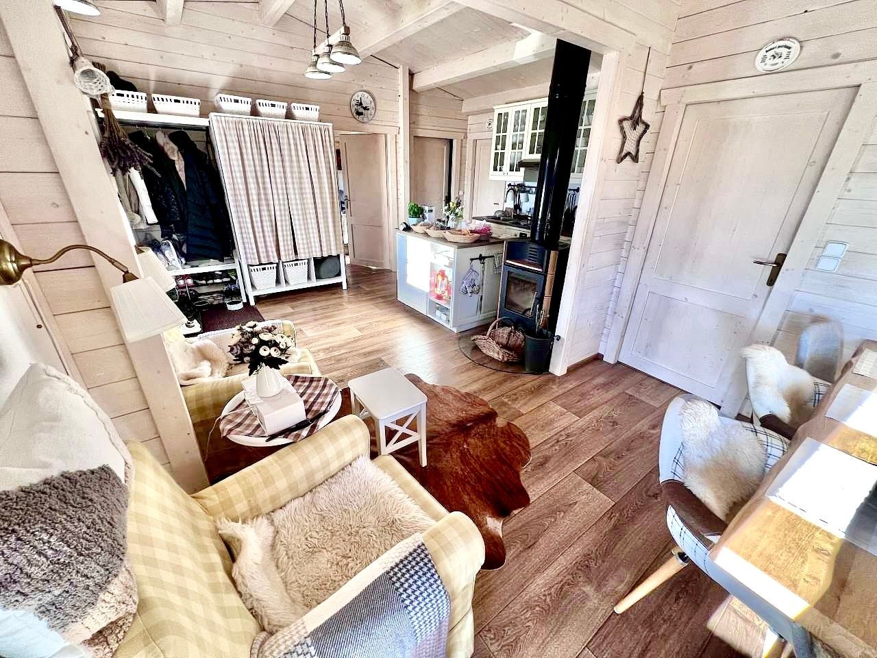 Cozy interior with wood floors, a light-colored sofa, and a table set for dining. Clothes are visible in the background.