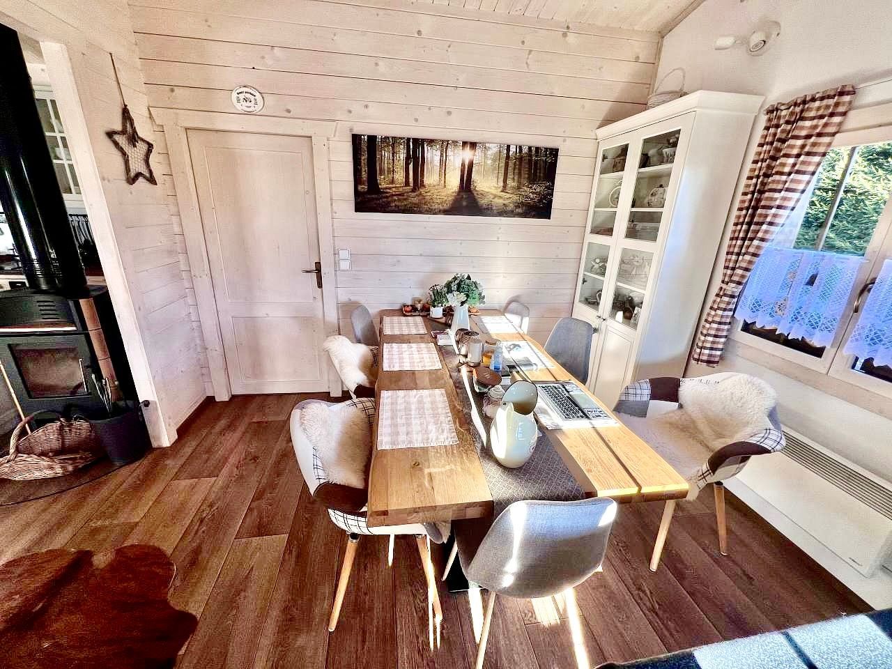 Cozy dining room with a wooden table set for a meal, surrounded by chairs and a large window.