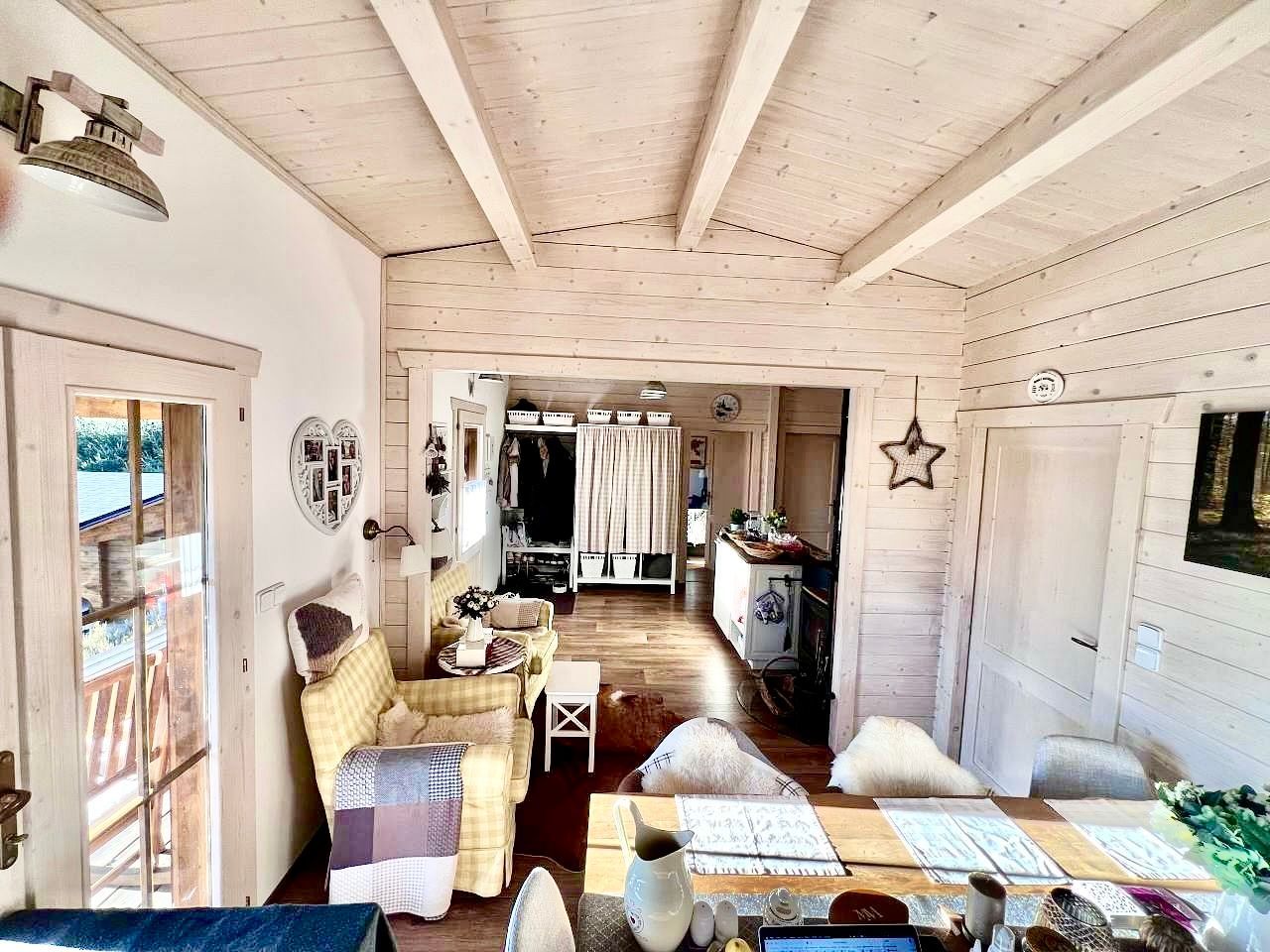 Bright interior room with wooden ceiling and walls, furniture, and open doorways to other rooms.