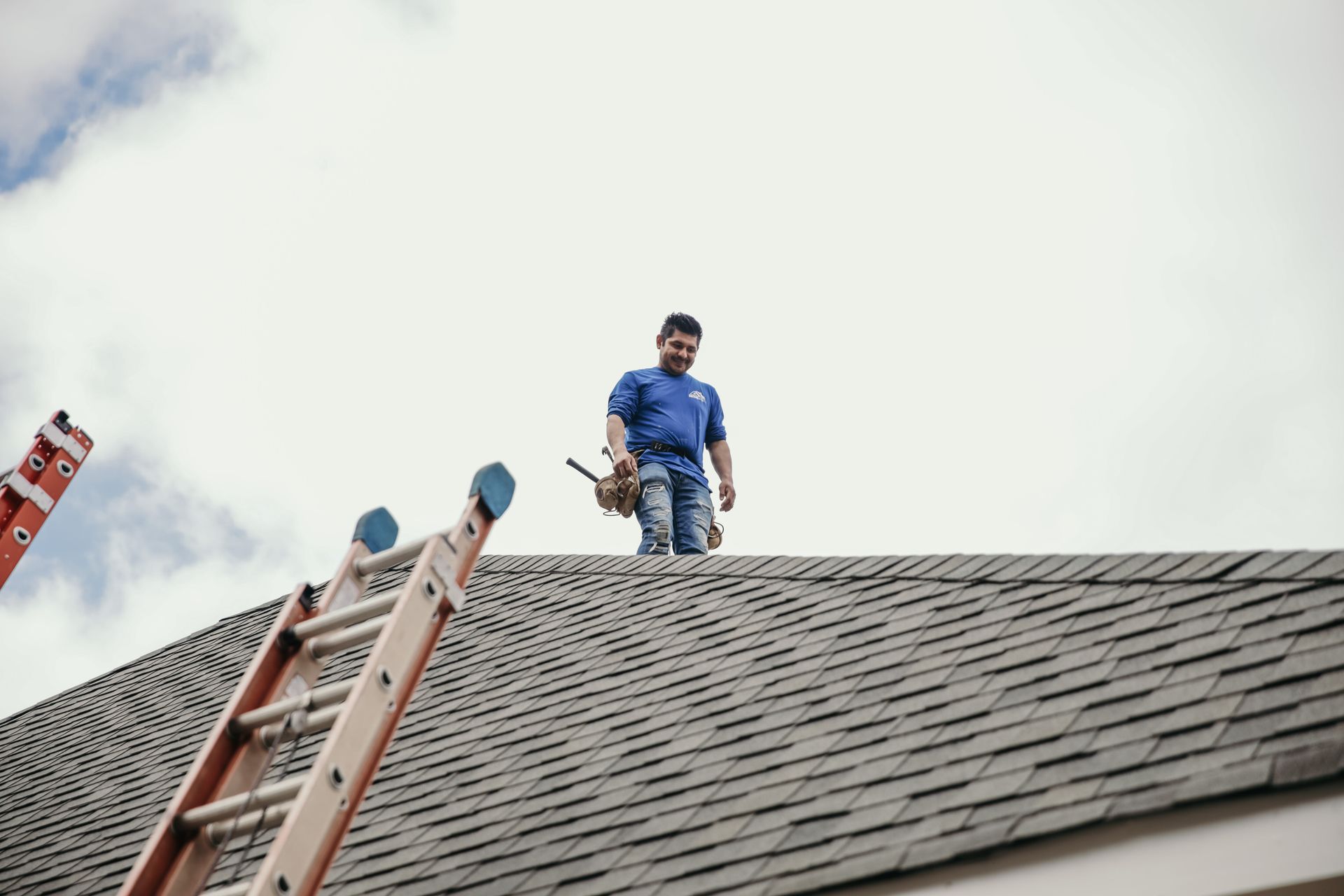 A roofer on top of a house checking for repairs