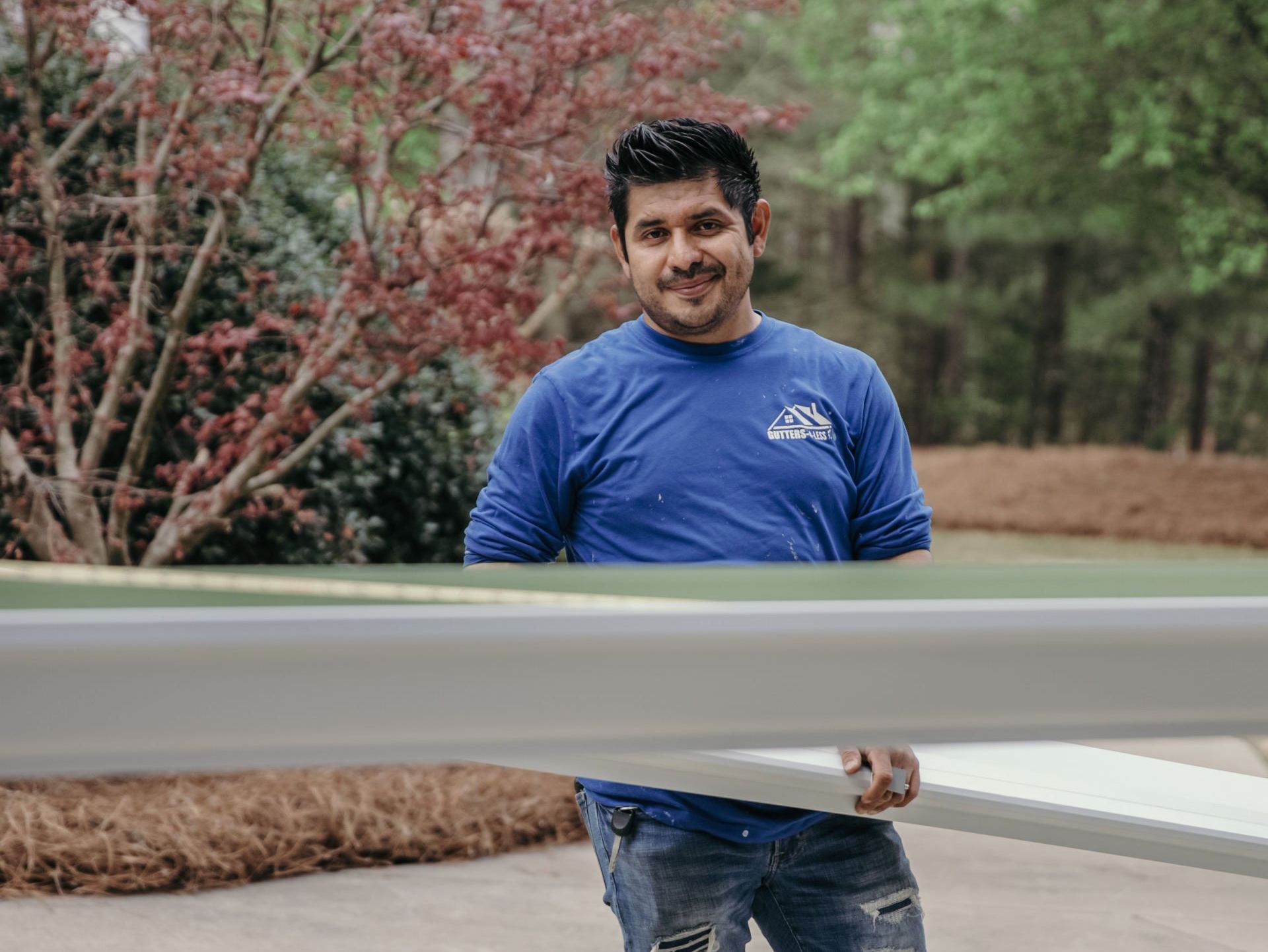 A man in a blue shirt is holding a large piece of metal.