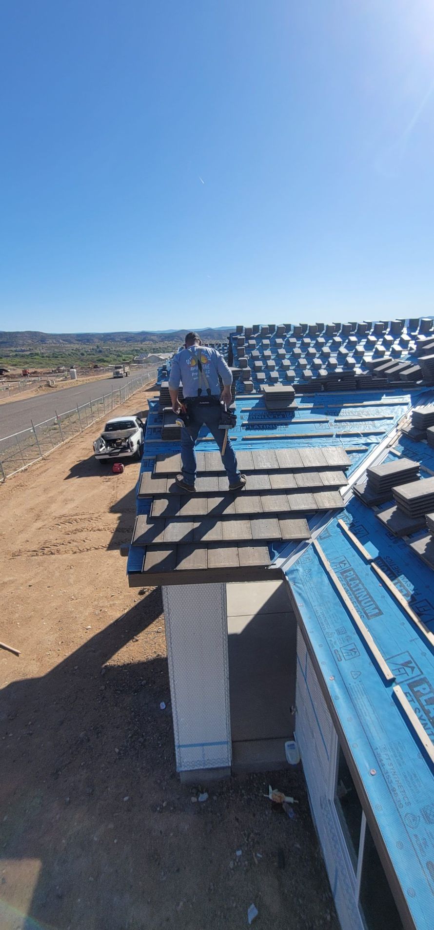 A man is standing on top of a blue roof.