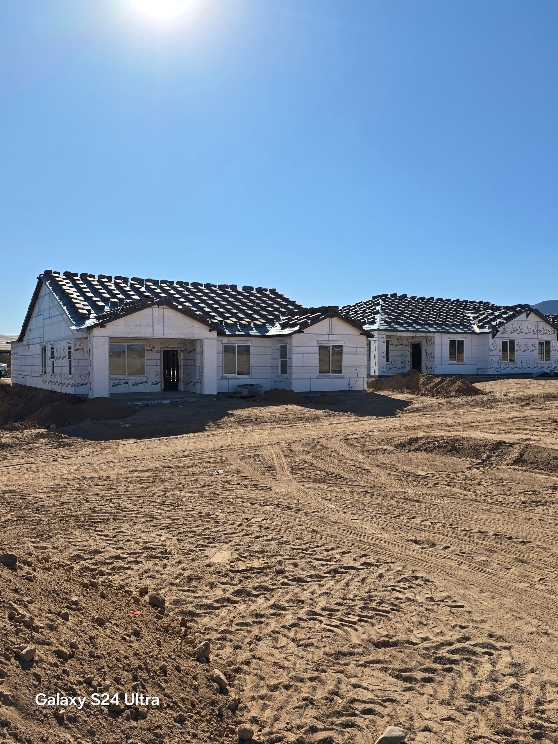 A house is being built in the middle of a dirt field.