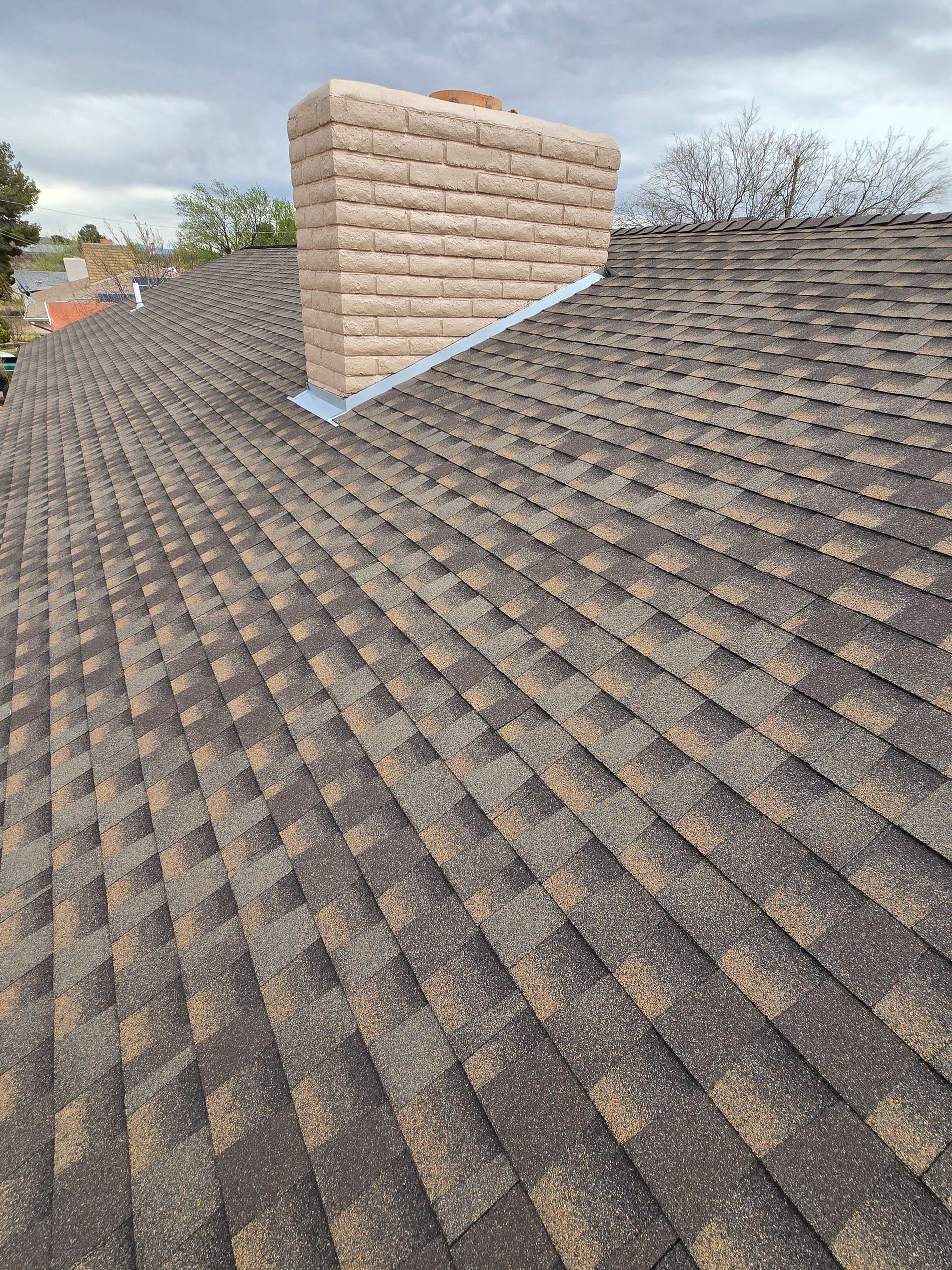 A man is kneeling on top of a roof while working on it.