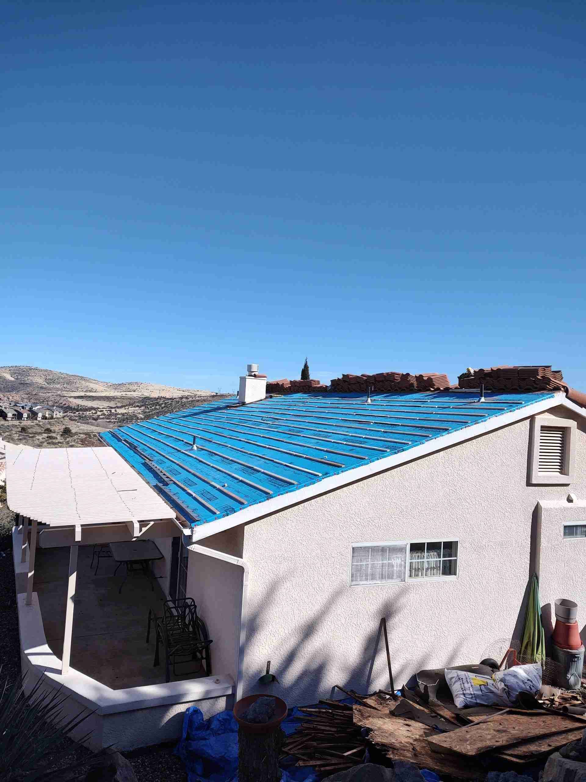 A white house with a blue roof is being remodeled.