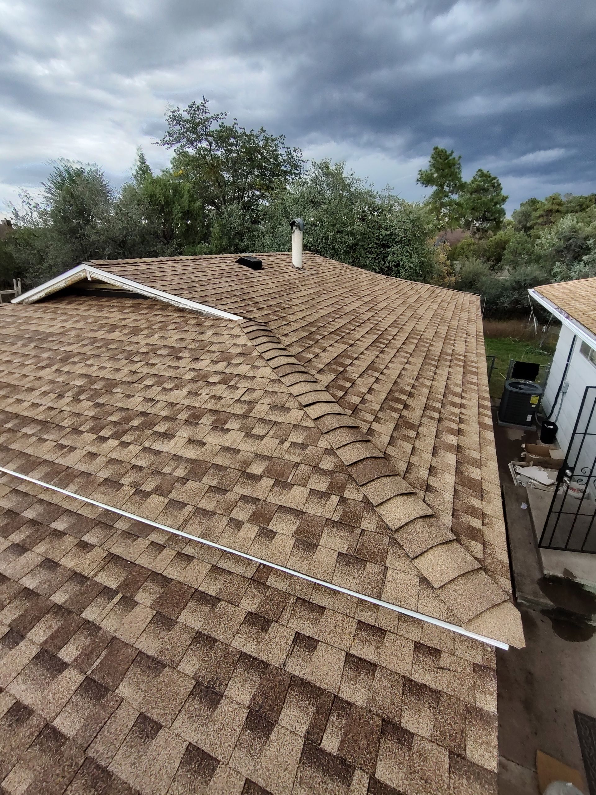 An aerial view of a roof of a house with a cloudy sky in the background.
