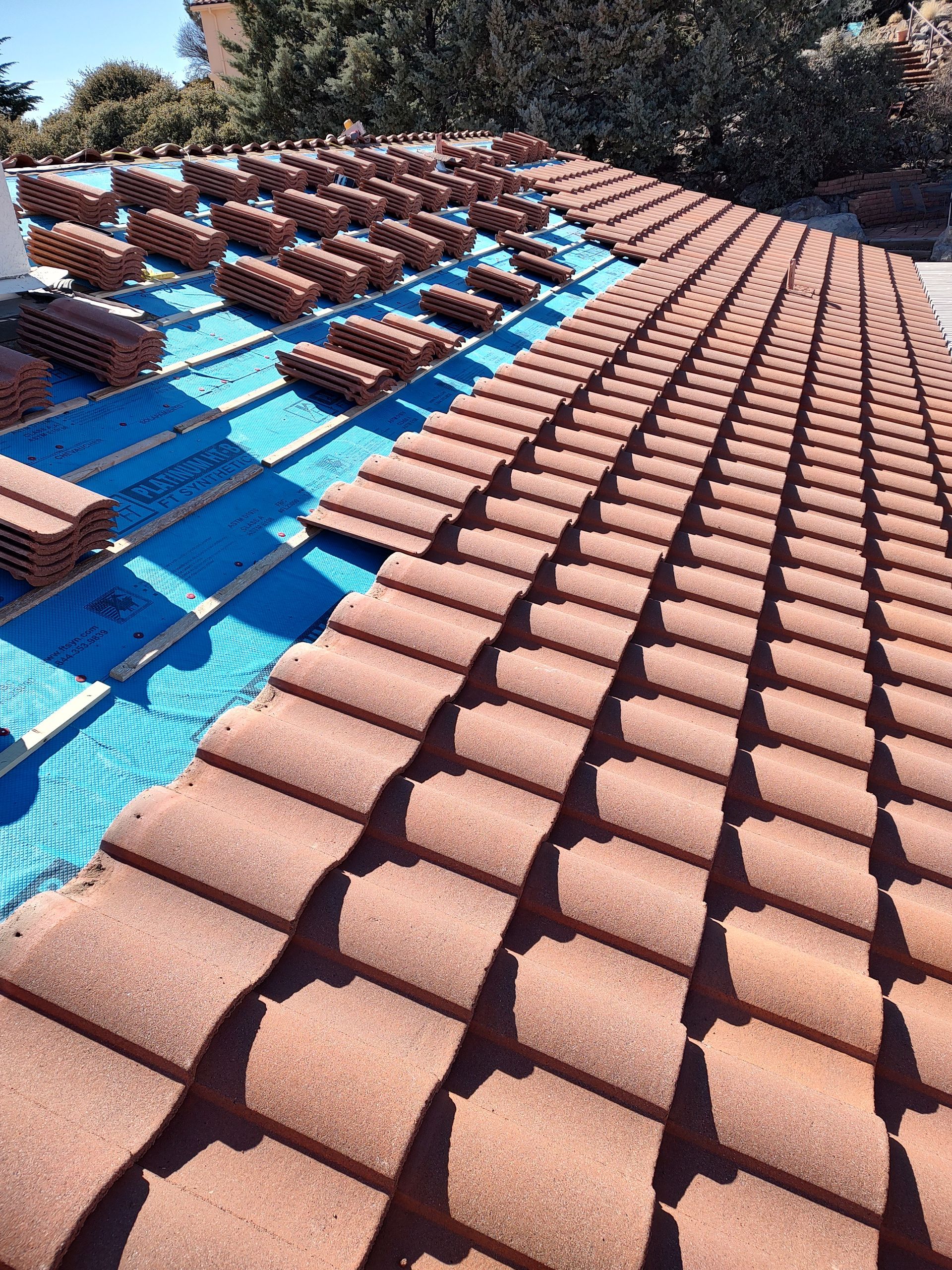 A man is standing on top of a blue roof.