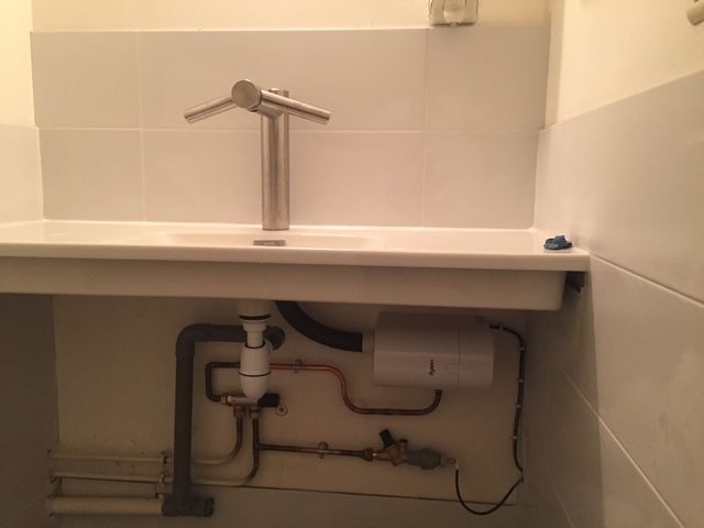 Un lavabo de salle de bain avec un robinet et des tuyaux en dessous.