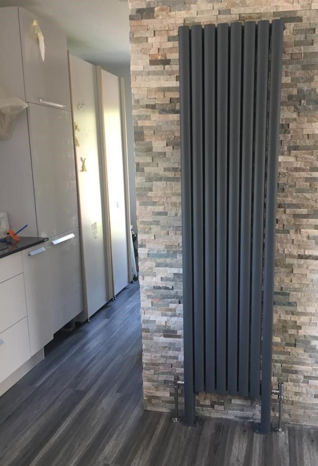 Une cuisine avec un radiateur gris contre un mur de briques.