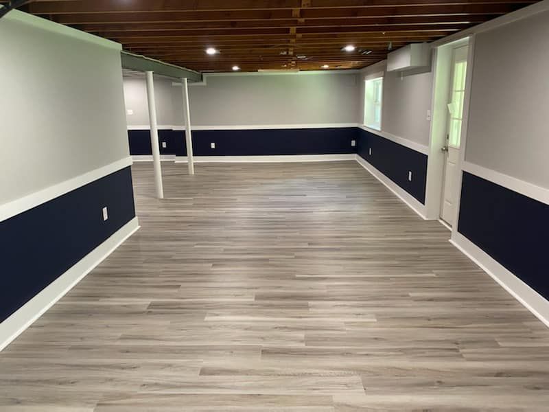 An empty basement with a wooden floor and blue and white walls