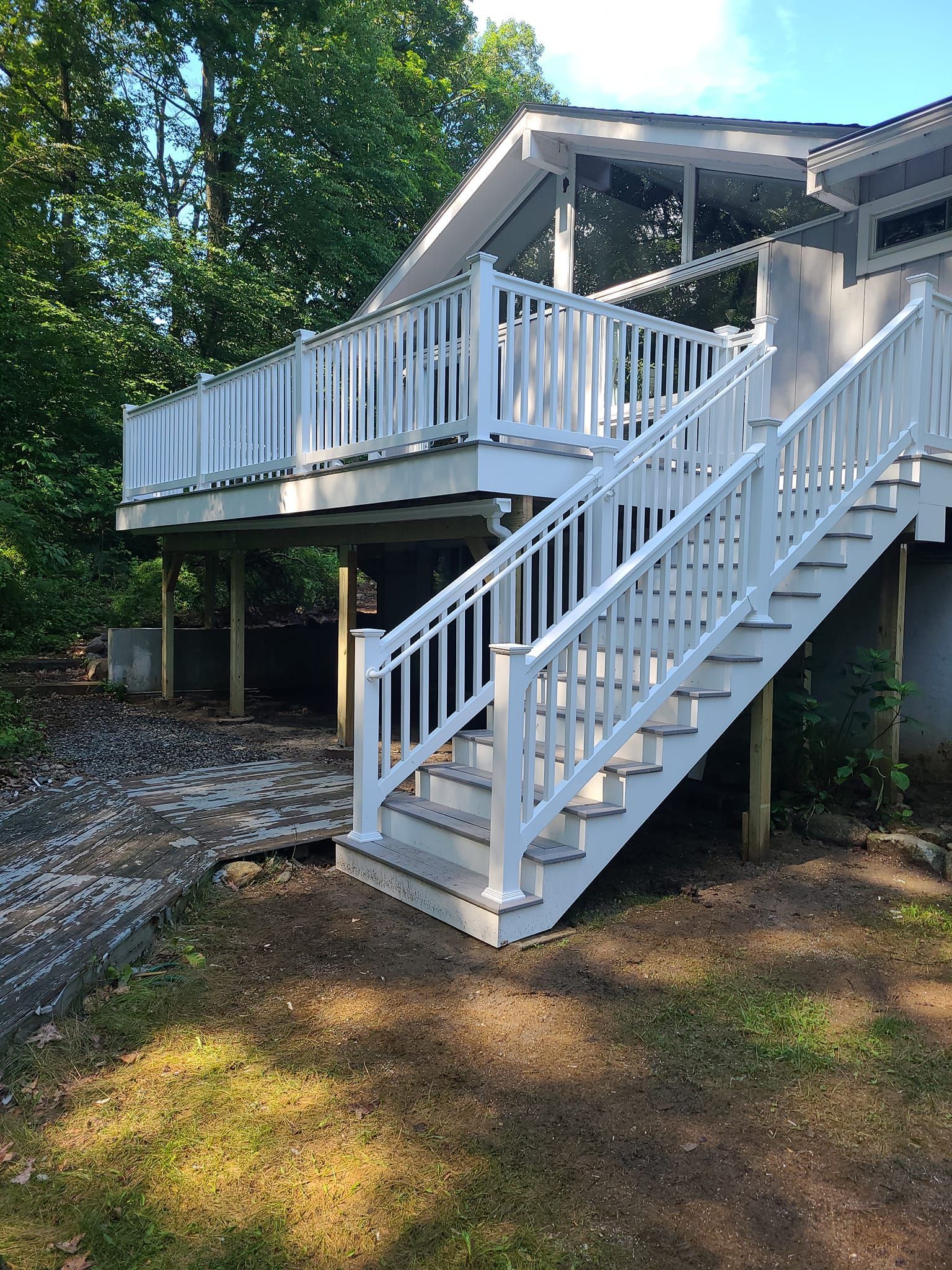 A white deck with stairs leading up to it.