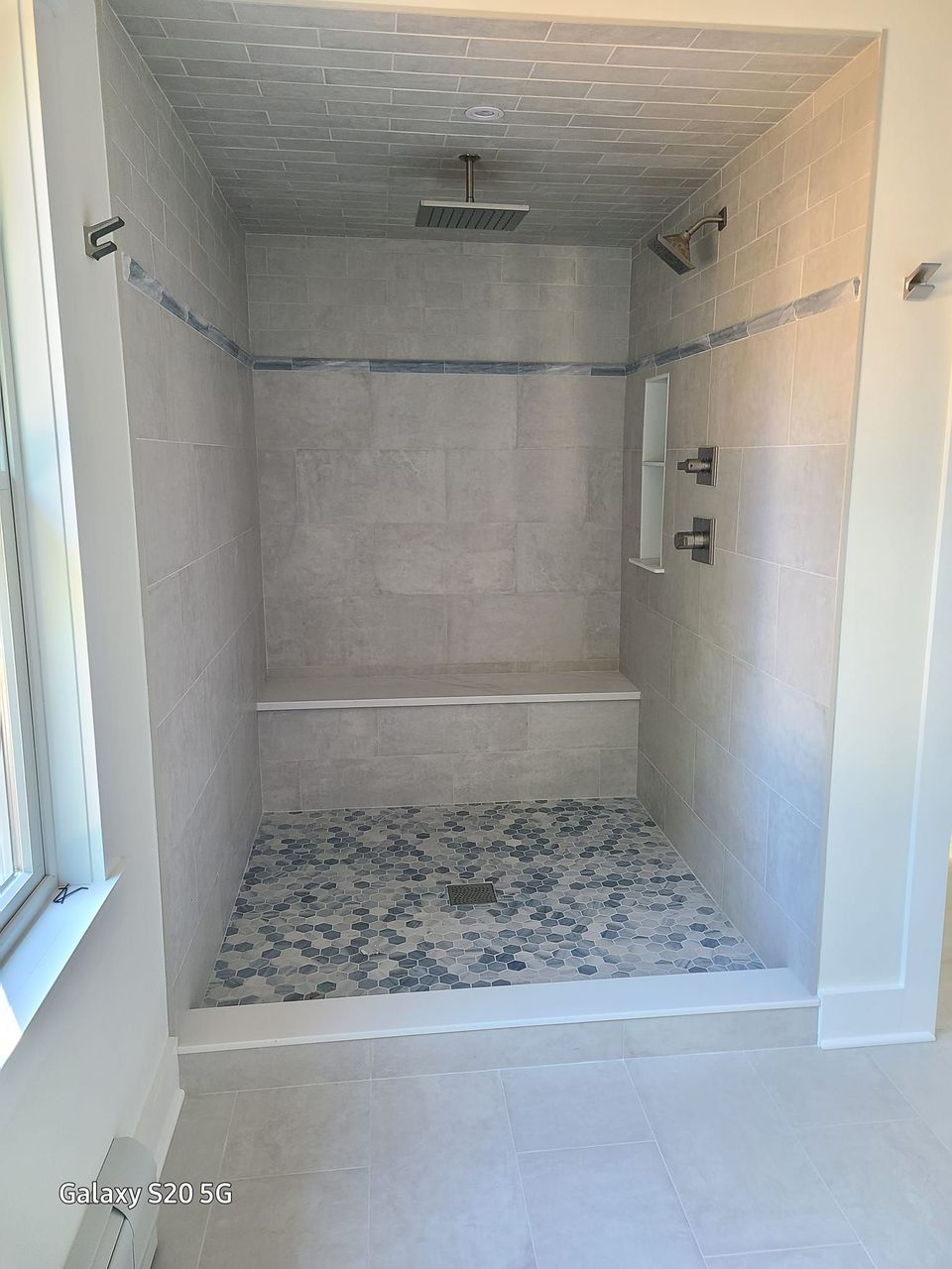A bathroom with a walk in shower and a window.