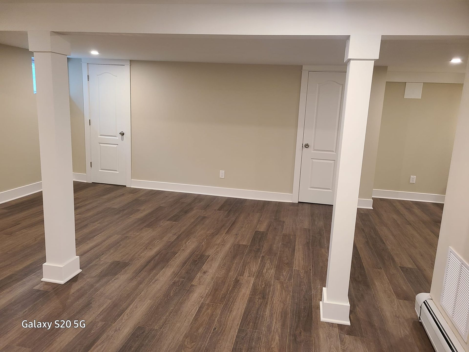 An empty basement with hardwood floors and white trim