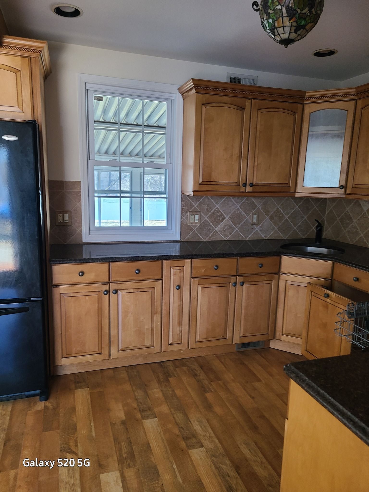 A kitchen with wooden cabinets and a black refrigerator.