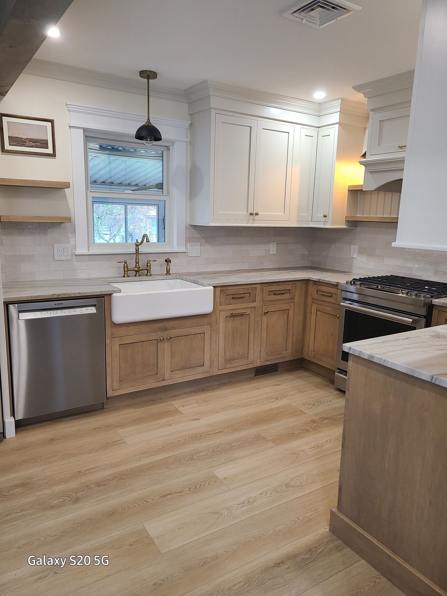 A kitchen with wooden cabinets , stainless steel appliances , a sink and a stove.