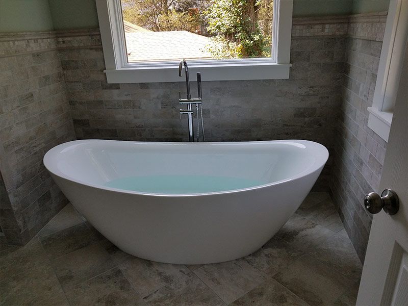A bathtub is sitting in a bathroom next to a window.