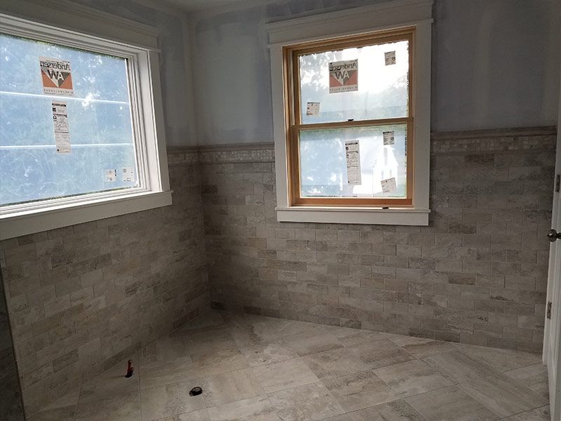 An empty bathroom with a window and tile walls