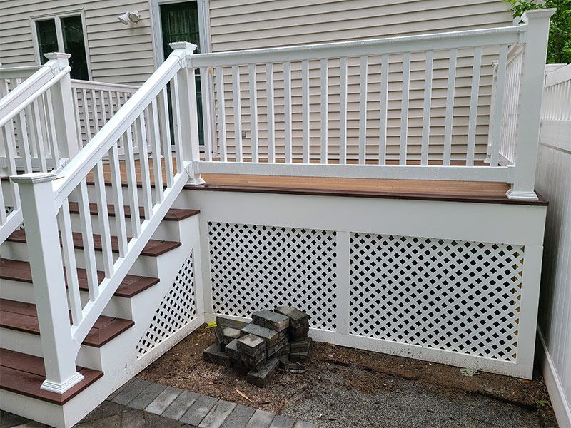 A white deck with wooden stairs and a white railing.