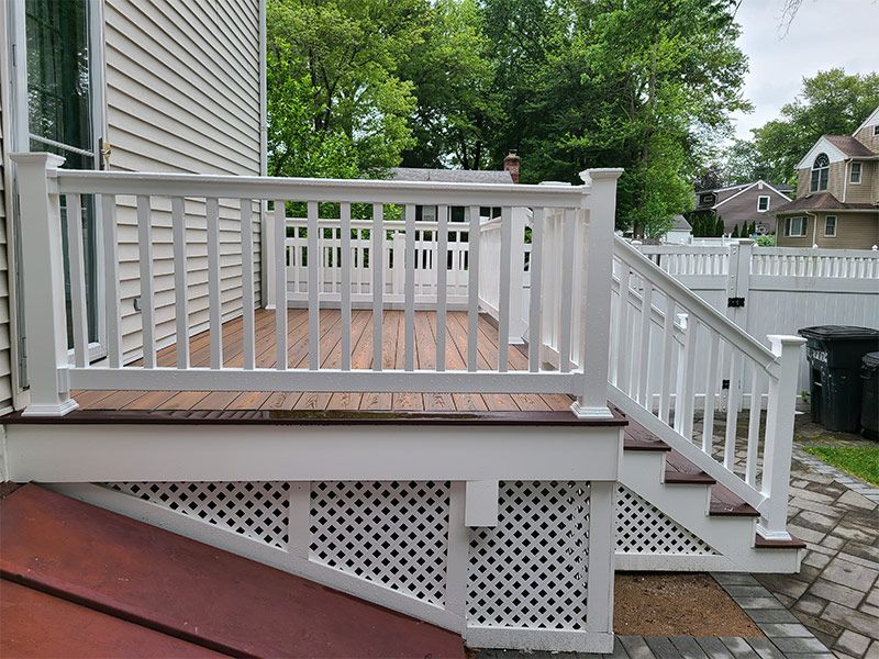 A white deck with stairs leading up to it and a white railing.