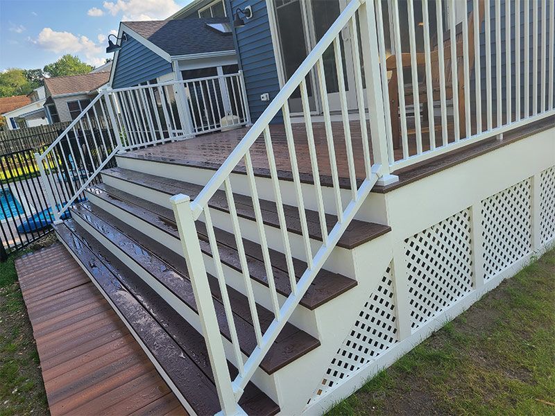 A deck with stairs leading up to it and a white railing.